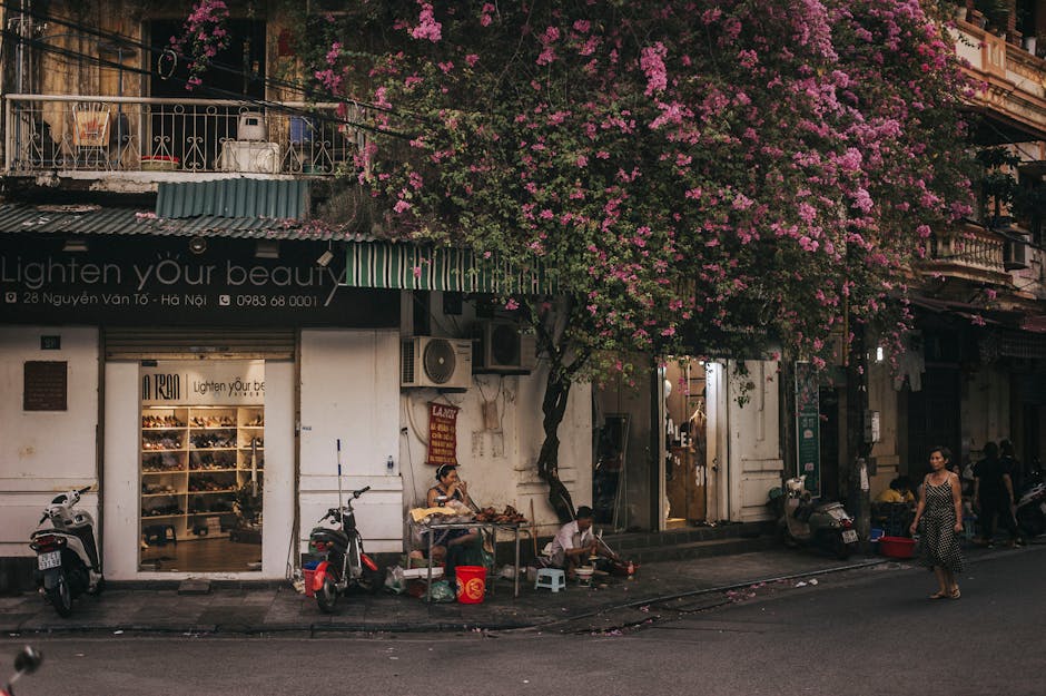 A bustling Hanoi street showcases vibrant life with a blooming tree and local vendors.
