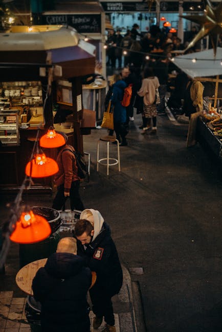 Warm, festive ambiance at an urban market during evening hours with people enjoying food and decorations.